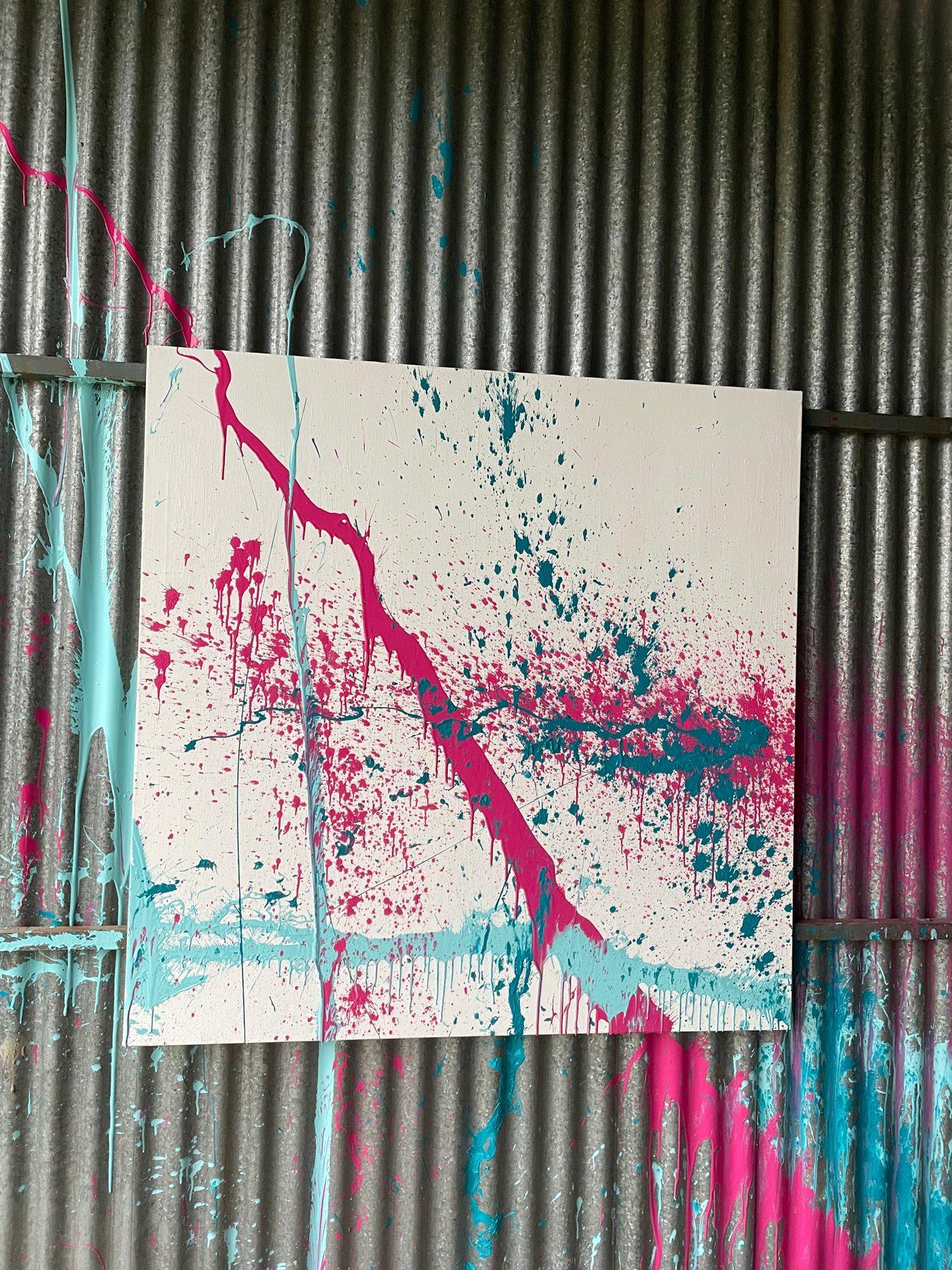 The Window by Alejandro Sánchez: a magenta and teal acrylic slash across a white canvas, against a corrugated steel barn wall